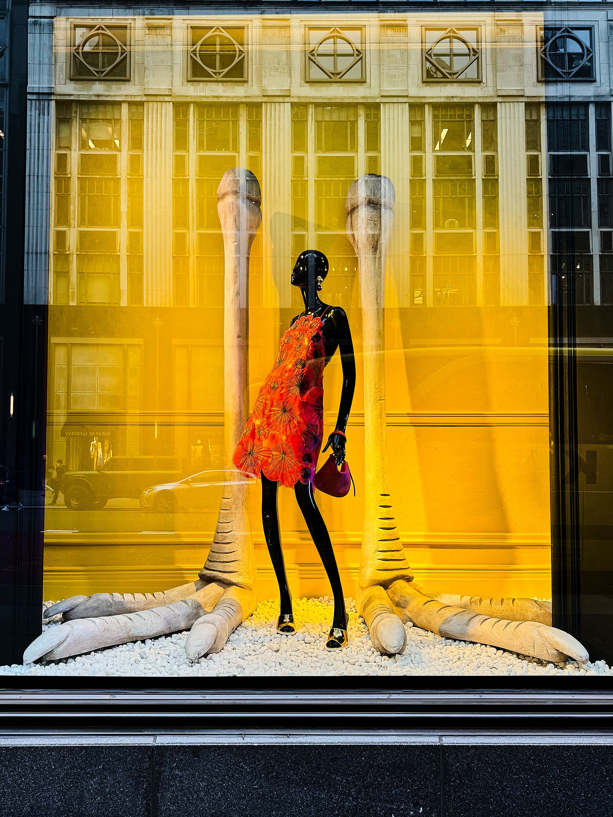 Black mannequin in a fashion storefront against a yellow backdrop, red floral dress, strong color contrast, urban fashion photograph with social commentary